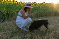 A woman in a hat and a white dress sits on a mown field Royalty Free Stock Photo