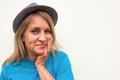 Woman in hat. White girl looks at camera, smiles and touches her cheeks with hand. Front portrait with positive face and long hair Royalty Free Stock Photo