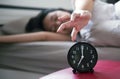 Woman hates getting stressed waking up early morning,Female stretching her hand to ringing alarm to turn off alarm clock in bedroo