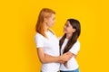 Woman have fun with cute child teen girl. Mommy and daughter hugging cudding isolated on yellow background studio