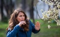 Woman having allergy symptoms in front of blooming tree Royalty Free Stock Photo