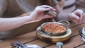 Woman having breakfast. Girl salting food served in frying pan in cafe for lunch