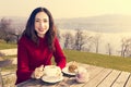 Woman having breakfast at an outdoor restaurant by lake