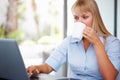 Woman having coffee at work. Business woman drinking coffee while working on laptop.