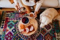 woman having a cup of tea at home during breakfast. Cute golden retriever dog besides. Healthy breakfast with fruits and sweets. Royalty Free Stock Photo