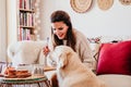 woman having a cup of tea at home during breakfast. Cute golden retriever dog besides. Healthy breakfast with fruits and sweets. Royalty Free Stock Photo