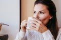 woman having a cup of tea at home during breakfast. Cute golden retriever dog besides. Healthy breakfast with fruits and sweets. Royalty Free Stock Photo