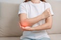 Woman having elbow ache during sitting on couch at home, muscle pain due to lateral epicondylitis or tennis elbow. injury, Health