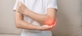 Woman having elbow ache during sitting on couch at home, muscle pain due to lateral epicondylitis or tennis elbow. injury, Health