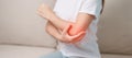 Woman having elbow ache during sitting on couch at home, muscle pain due to lateral epicondylitis or tennis elbow. injury, Health