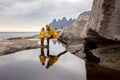 Woman, having fun with child in Tungeneset, Senja, Norway, jumping over big puddle, leaving reflection in water