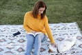 woman having fun with jack russell dog in park, sitting on blanket during autumn season. Woman reading a book while cuddling dog. Royalty Free Stock Photo