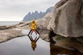 Woman, having fun with toddler child in Tungeneset, Senja, Norway, jumping over big puddle, making reflection in water