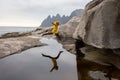 Woman, having fun in Tungeneset, Senja, Norway, jumping over big puddle, making reflection in water