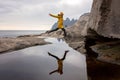 Woman, having fun in Tungeneset, Senja, Norway, jumping over big puddle, making reflection in water