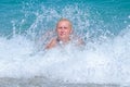 A woman having fun in the waves of the sea which are splashing her. The beautiful woman mother of three in bikini