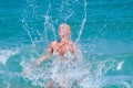 A woman having fun in the waves of the sea which are splashing her. The beautiful woman mother of three in bikini