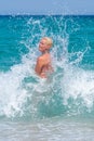 A woman having fun in the waves of the sea which are splashing her. The beautiful woman mother of three in bikini