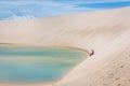 Woman having a good time, rolling down a huge sand dune in a amazing scenario, natural pool lagoon in the bottom. North of Brasil,