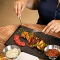 Woman having lunch in restaurant. Close up shot of female hands with knife, fork and Food plate, Side view. Appetizer