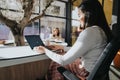 Woman having phone call and smiling while working in sunlit, pleasant office atmosphere on the lap top.