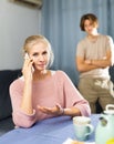 Woman having phone conversation at home against background of upset teenage son Royalty Free Stock Photo