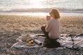 Woman having picnic at beach with tea in thermos.