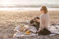 Woman having picnic at beach with tea in thermos.