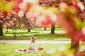 Woman having picnic on sunny spring day in park during cherry blossom season Royalty Free Stock Photo