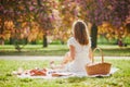 Woman having picnic on sunny spring day in park during cherry blossom season Royalty Free Stock Photo