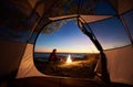 Woman having a rest at night camping near tourist tent, campfire on sea shore under starry sky Royalty Free Stock Photo