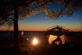 Woman having a rest at night camping near tourist tent, campfire on sea shore under starry sky Royalty Free Stock Photo