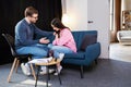 Woman having session with psychologist, sitting on couch at clinic. The woman is very upset, the psychotherapist is trying to help Royalty Free Stock Photo