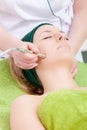 Woman having stimulating facial treatment from therapist. Beauty salon.