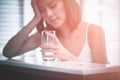 Woman with a headache holds glass of water,depth and shallow,focus on pill