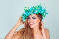 Woman with headband from blue flowers touching chin and hair flirting