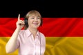Woman in headphones on a background of the colored flag of the Federal Republic of Germany on the texture of the fabric, silk with