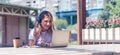 Woman in headphones having a video call with laptop. Happy and smiling girl working outside and drinking coffee. Using computer Royalty Free Stock Photo