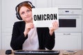 A woman with headphones holds a sheet of paper with the text of the new variant covid virus Omicron, mockup Royalty Free Stock Photo
