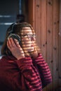 A woman with headphones looks through the blinds at the early morning sunlight. Royalty Free Stock Photo