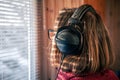 A woman with headphones looks through the blinds at the early morning sunlight. Royalty Free Stock Photo
