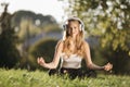 Woman in headphones meditating at green park Royalty Free Stock Photo