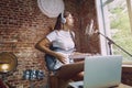 Woman recording music, playing guitar and singing at home