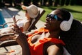 Woman in headphones sunbathing on sun bed at pool Royalty Free Stock Photo