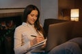 A woman with headphones working remotely on her laptop sitting on the sofa Royalty Free Stock Photo