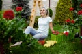 Woman in headphones works with flowers in garden