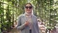 woman in headscarf and sunglasses smiling in garden arch