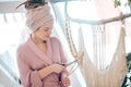 Woman in a headwear cutting yarn while weaving macrame