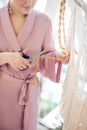 Woman in a headwear cutting yarn while weaving macrame