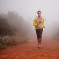 Woman, health and running in forest with fitness for exercise, morning routine and workout with fog and confidence Royalty Free Stock Photo